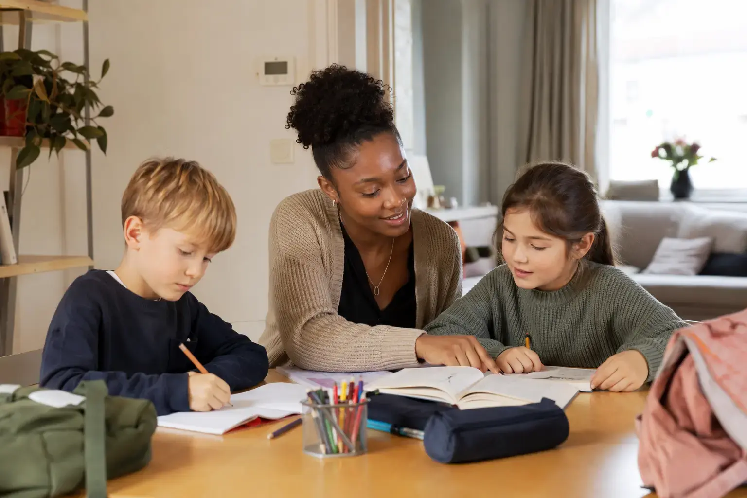 Babysitter helpt twee kinderen thuis met huiswerk